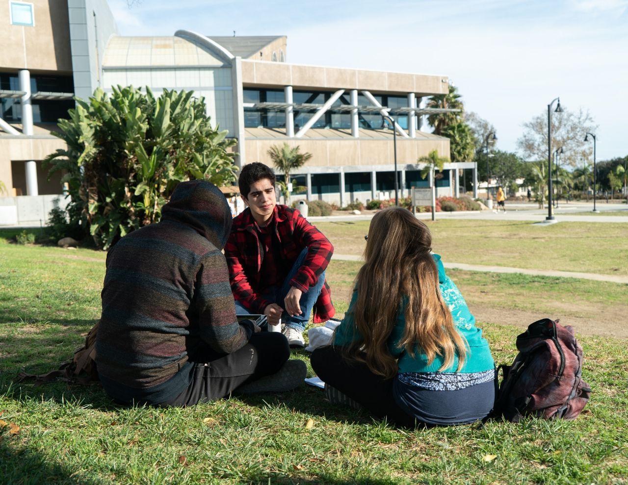 Three students sitting on the lawn